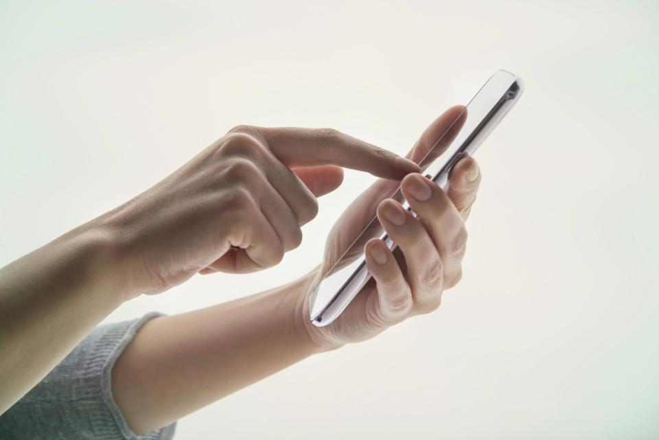 Young woman's hands using a portable information device on white background