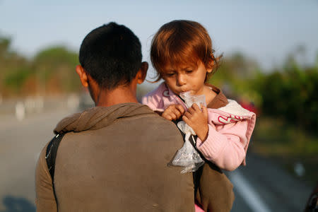 A Honduran migrant carries his daughter as they walk during their journey towards the United States, in Mapastepec, Mexico April 20, 2019. REUTERS/Jose Cabezas