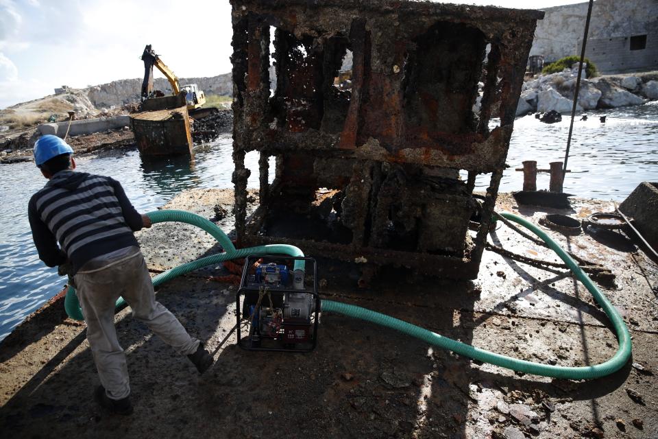 A worker pumps out water from a shipwreck during a raising operation, on Salamina island, west of Athens, on Friday, Nov. 8, 2019. Greece this year is commemorating one of the greatest naval battles in ancient history at Salamis, where the invading Persian navy suffered a heavy defeat 2,500 years ago. But before the celebrations can start in earnest, authorities and private donors are leaning into a massive decluttering operation. They are clearing the coastline of dozens of sunken and partially sunken cargo ships, sailboats and other abandoned vessels. (AP Photo/Thanassis Stavrakis)