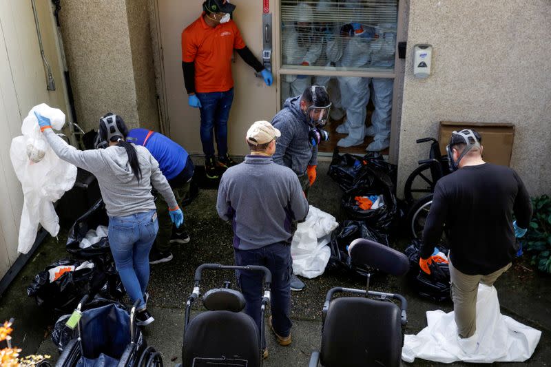 Members of a Servpro cleaning crew take off their protective gears as they exit the Life Care Center of Kirkland, the Seattle-area nursing home at the epicenter of one of the biggest coronavirus outbreaks in the United States, in Kirkland