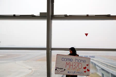 FILE PHOTO: A woman holds a sign of support and hope for the passengers of the missing Malaysia Airlines flight MH370 she made and brought to the Kuala Lumpur International Airport March 11, 2014. REUTERS/Damir Sagolj/File Photo