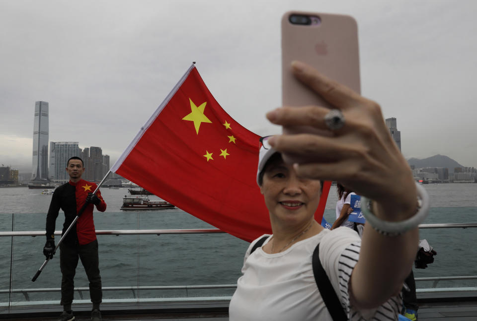 In this Saturday, Aug. 17, 2019 file photo, pro-China supporters take a selfie with a Chinese national flag to support police and anti-violence during a rally at a park in Hong Kong. Twitter said Monday it has suspended more than 200,000 accounts that it believes were part of a Chinese government influence campaign targeting the protest movement in Hong Kong. (AP Photo/Vincent Yu)