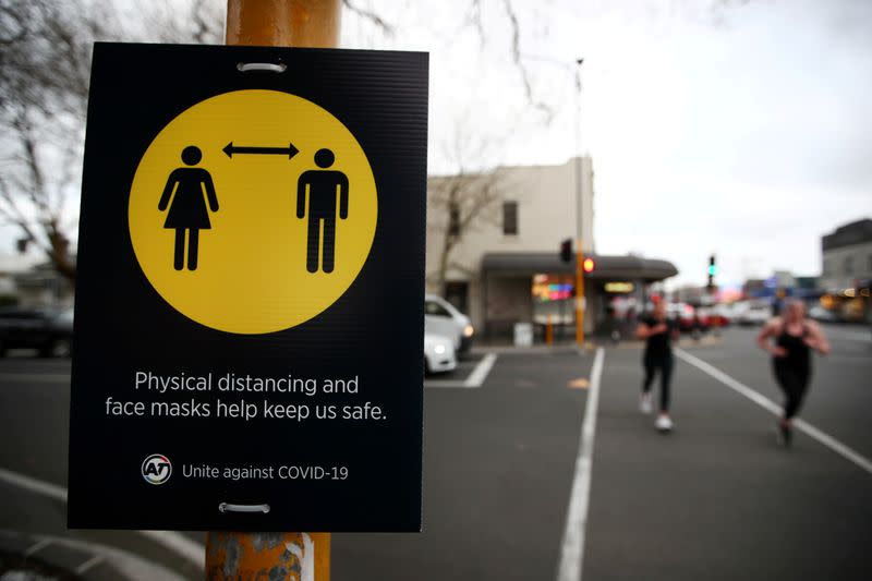 FILE PHOTO: People jog past a social distancing sign in Auckland, New Zealand, August 31, 2020