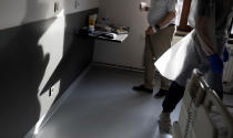 A Belgian Army medic works in a room after delivering lunch to a patient with COVID-19 at the St. Michiel Hospital in Brussels, Tuesday, Nov. 24, 2020. The Belgian military has been called into several hospitals and care homes to alleviate the stress on healthcare personnel. (AP Photo/Virginia Mayo)