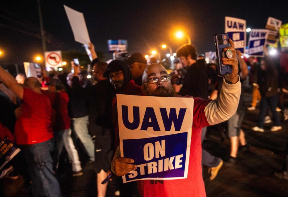 Members of theUnited Auto Workers picket and hold signs outside of the UAW Local 900 headquarters across the street from the Ford Assembly Plant in Wayne, Michigan on 15 September. (AFP via Getty Images)