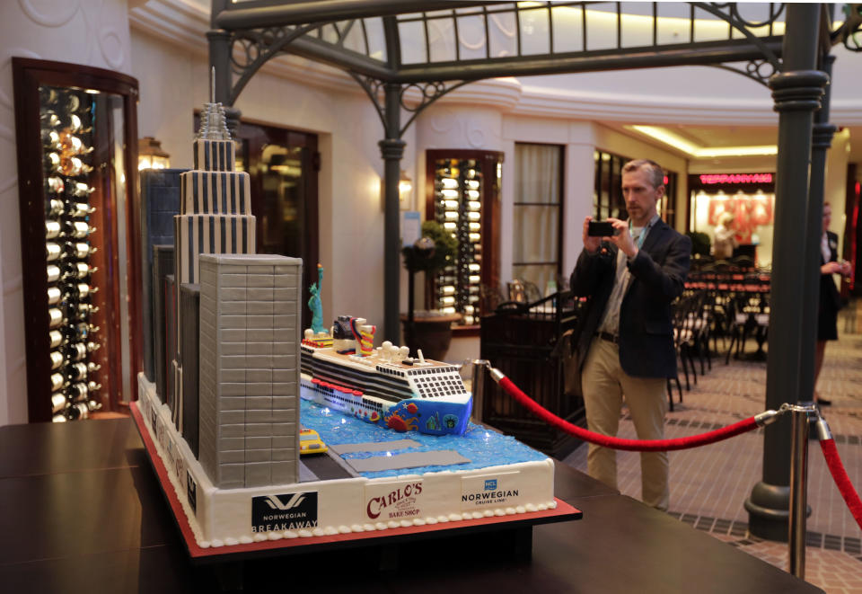 A passenger stops to photograph a cake by Cake Boss Buddy Valastro aboard the Norwegian Cruise Line's new ship, Norwegian Breakaway, which was christened in New York, Wednesday, May 8, 2013. The New York-themed ship has an outpost of Vlastro's Hoboken, N.J., bakery, Carlo's Bake Shop. (AP Photo/Richard Drew)