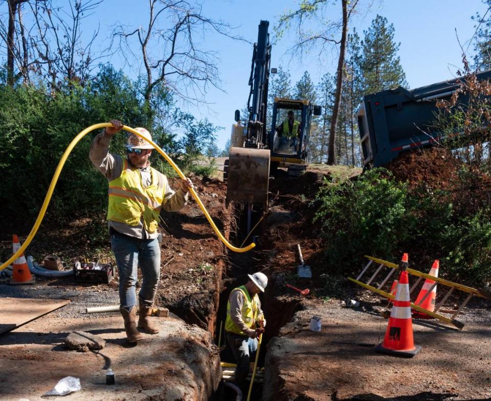 PG&E crew member Jason Haase, in the trench, installs underground utilities to home sites along Travis Road in Paradise in 2022. PG&E is placing all utilities for electric and gas underground as part of a wildfire safety effort in Paradise.