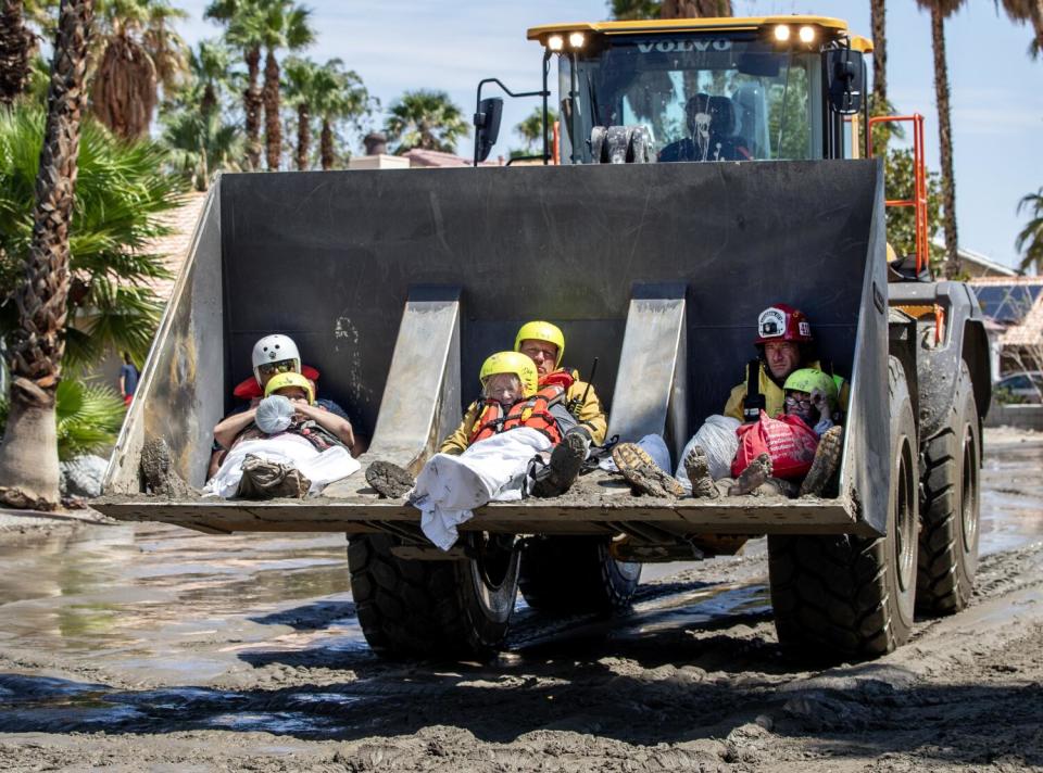 People are evacuated in a front-end loader.