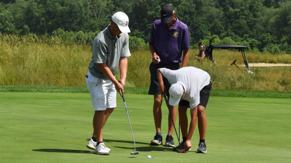 Bloomington South's Nick Bellush (left) taps in a putt on the 18th hole at Prairie View Golf Club as Westfield's Jake Cesare (right) and Guerin Catholic's Connor McNeely look on during day two of the IHSAA boys golf state finals. (Seth Tow/Herald-Times)