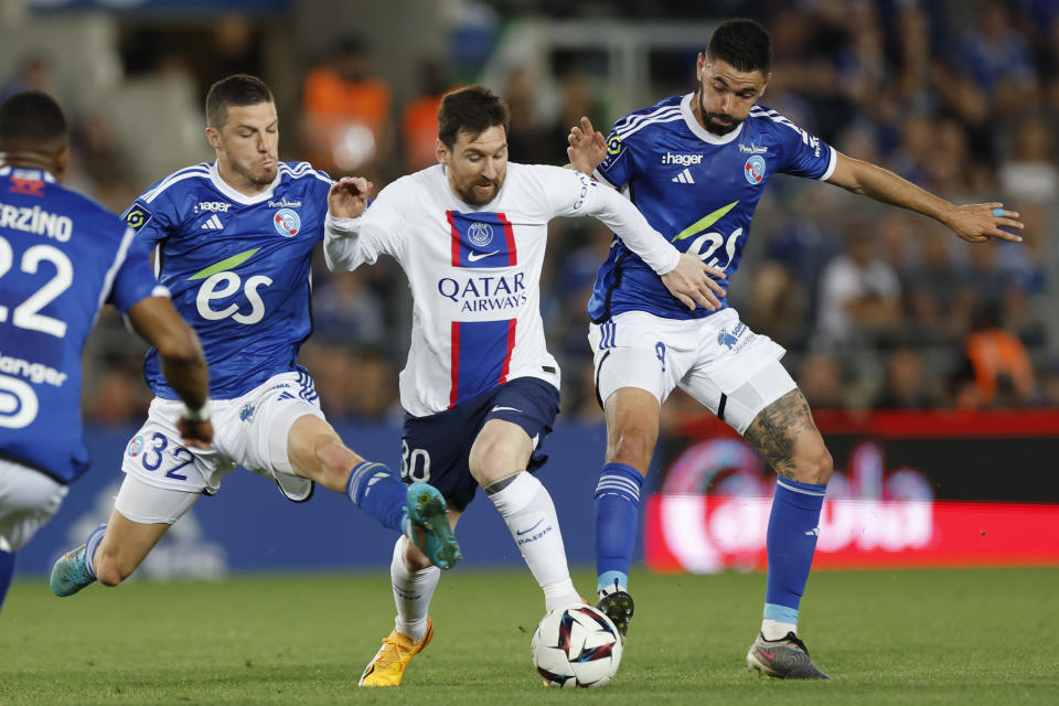 Lionel Messi (centro) del Paris Saint-Germain pugna el balón con Frederic Guilbert (izquierda) y Kevin Gameiro (derecha) de Estrasburgo en el empate 1-1 en el partido de la liga francesa, el sábado 27 de mayo de 2023. (AP Foto/Jean-Francois Badias)