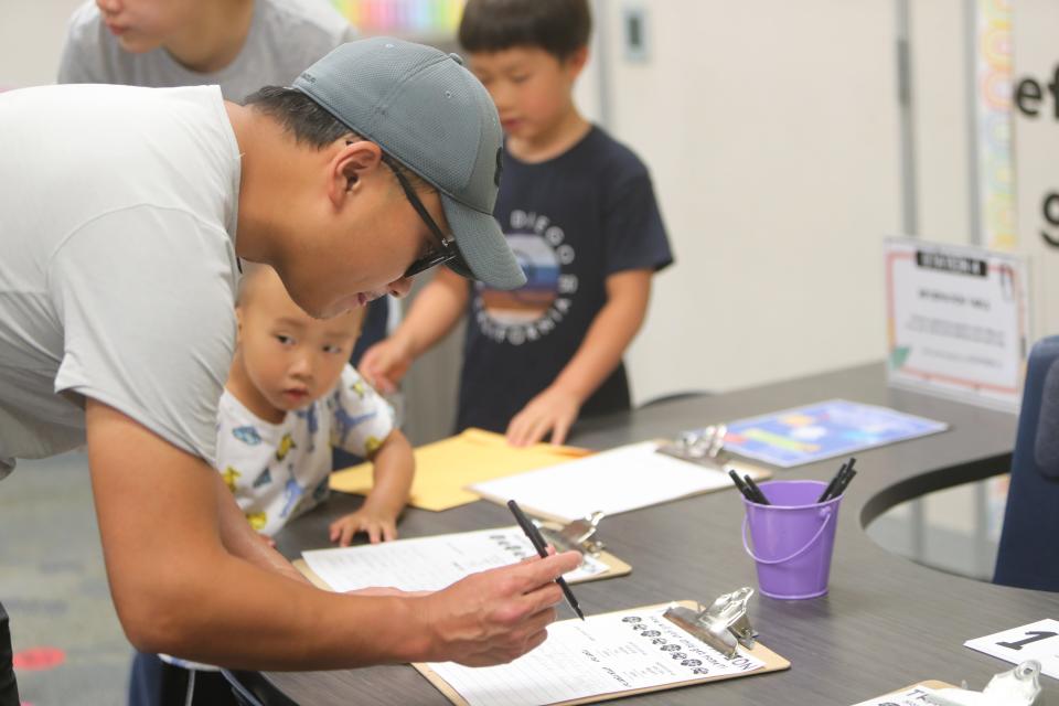 Guanheng Yan fills out a piece of paper for his child at Kyrene de la Mirada Leadership Academy in Chandler on July 17, 2023, during the academy's back-to-school event.