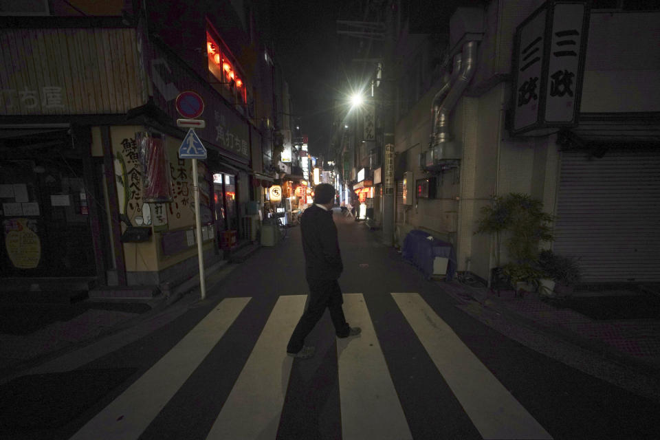 Un hombre hombre solitario pasea por la zona de centros nocturnos de Shimbashi, normalmente llena, el miércoles 8 de abril de 2020 en Tokio. El primer ministro japonés Shinzo Abe declaró el martes estado de emergencia para Tokio y otras seis prefecturas para frenar la propagación del coronavirus. (Foto AP/Eugene Hoshiko)