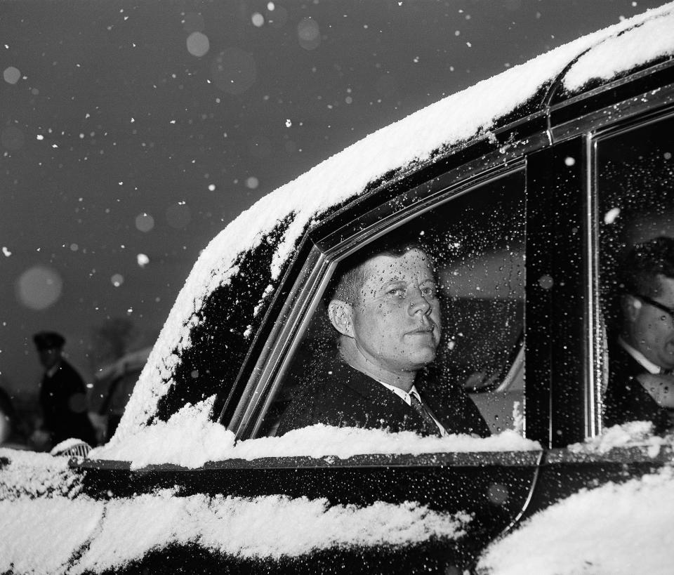 FILE - In this Dec. 9, 1961 file photo, U.S. President John Kennedy looks out of the window from a snow-covered limousine at Andrews Air Force Base, Md. near Washington after his return from Florida. (AP Photo/Byron Rollins)