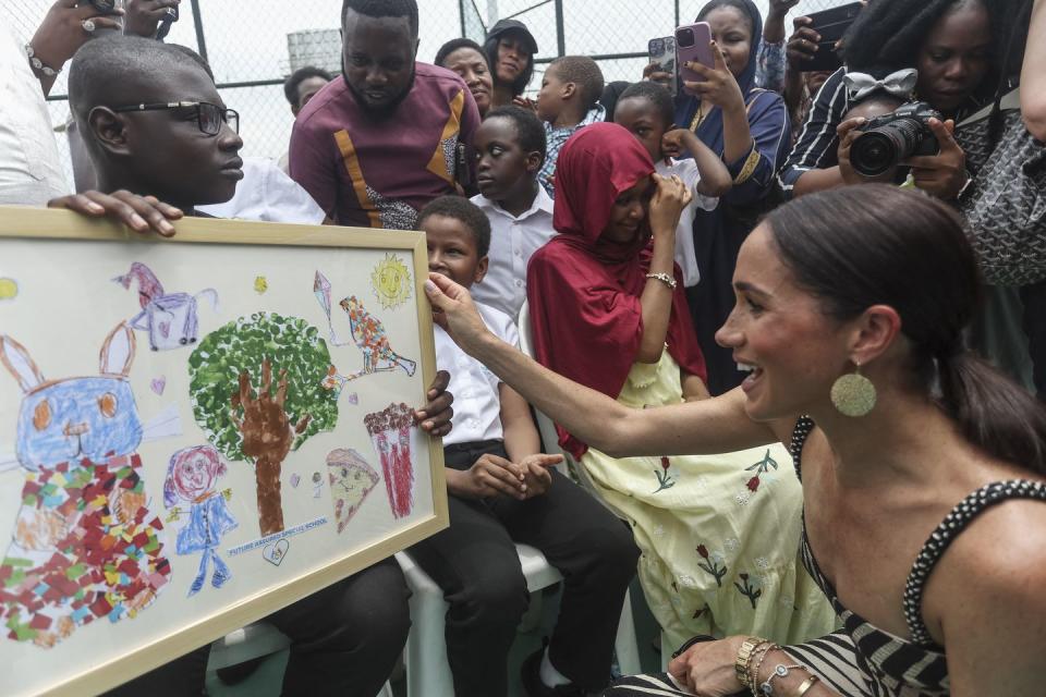 britains meghan r, duchess of sussex, receives an artwork upon her arrival with britains prince harry unseen, duke of sussex, for an exhibition sitting volleyball match at nigeria unconquered, a local charity organisation that supports wounded, injured, or sick servicemembers, in abuja on may 11, 2024 as they visit nigeria as part of celebrations of invictus games anniversary photo by kola sulaimon afp photo by kola sulaimonafp via getty images