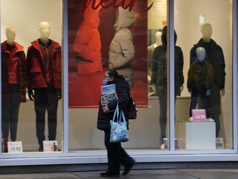 A pedestrian wears a mask while passing by a window display in a clothing store late Monday, Dec. 28, 2020, in downtown Denver. (AP Photo/David Zalubowski)