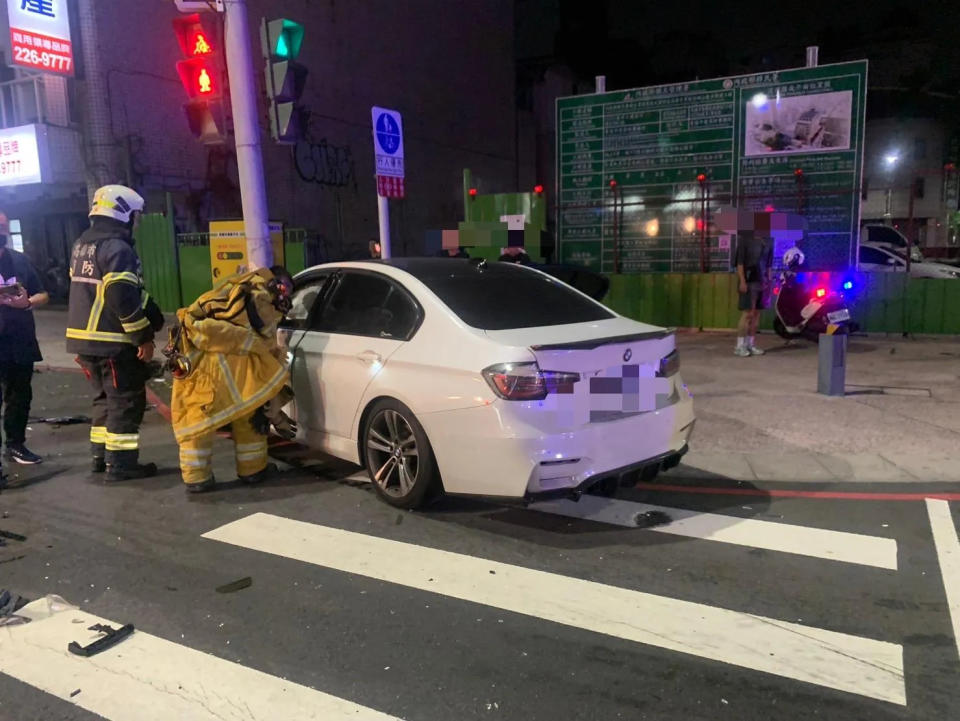 <strong>白色BMW被撞後失控撞上路邊燈桿，駕駛受困車上。（圖／翻攝畫面）</strong>