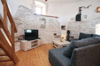 <p>The home features a modern living room with stone walls and wood floors. (Airbnb) </p>