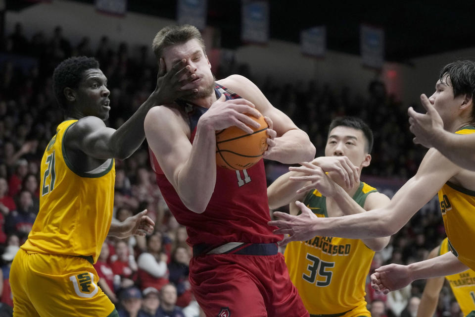 Saint Mary's center Mitchell Saxen, middle, is fouled while driving to the basket between San Francisco forward Ndewedo Newbury, left, forward Junjie Wang (35) and guard Mike Sharavjamts during the first half of an NCAA college basketball game in Moraga, Calif., Tuesday, Feb. 20, 2024. (AP Photo/Jeff Chiu)