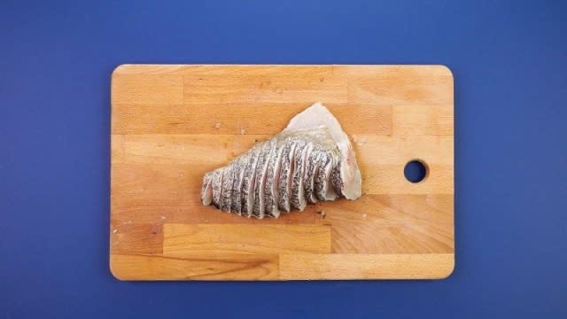 Sliced fish in peacock style on wooden chopping board