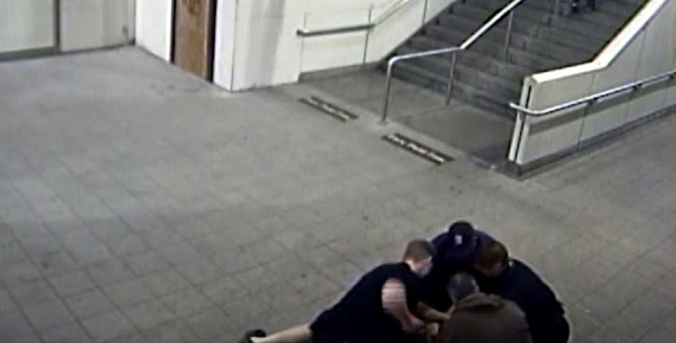 Surveillance video taken at the Commercial-Broadway SkyTrain station on May 24, 2017, shows Const. Beau Spencer, left, preparing to punch a suspect while constables Josh Wong, Brandon Blue and Gregory Jackson hold him down.  (CBC - image credit)
