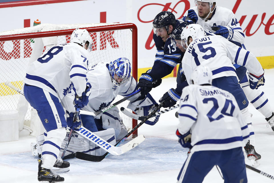 Winnipeg Jets' Pierre-Luc Dubois (13) and Paul Stastny (25) scramble for the puck in front of Toronto Maple Leafs goaltender Jack Campbell (36) as TJ Brodie (78) and Alexander Kerfoot (15) defend during the first period of an NHL hockey game Thursday, April 22, 2021, in Winnipeg, Manitoba. (John Woods/The Canadian Press via AP)