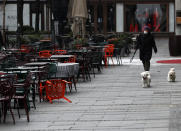 A woman walks with dogs in a deserted street amid the coronavirus outbreak in downtown Belgrade, Serbia, Thursday, March 26, 2020. (AP Photo/Darko Vojinovic)