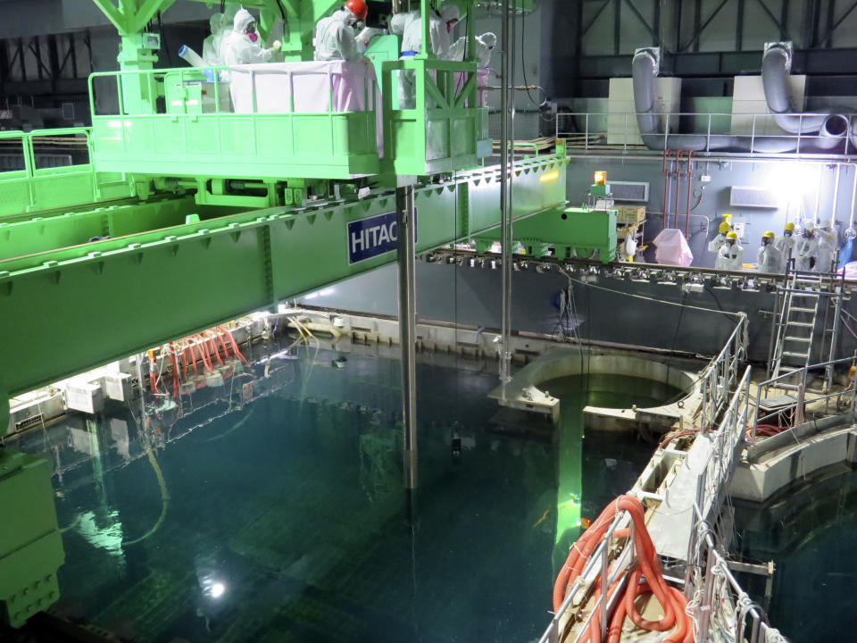 FILE - In this Nov. 18, 2013 file photo released by Tokyo Electric Power Co. (TEPCO), workers try to remove radioactive fuel rods from the Unit 4 building at the crippled Fukushima Dai-ichi nuclear power plant in Okuma, Fukushima Prefecture, northeastern Japan. Eyeing dozens of aging reactors at home and hundreds of others worldwide that eventually need to be retired, Japanese industry sees a profitable market for decommissioning expertise. (AP Photo/Tokyo Electric Power Co., File)