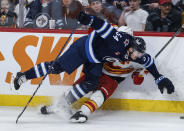 Winnipeg Jets' Dylan Samberg (54) and Calgary Flames' Rasmus Andersson (4) collide during the second period of an NHL hockey game Thursday, April 4, 2024, in Winnipeg, Manitoba. (John Woods/The Canadian Press via AP)