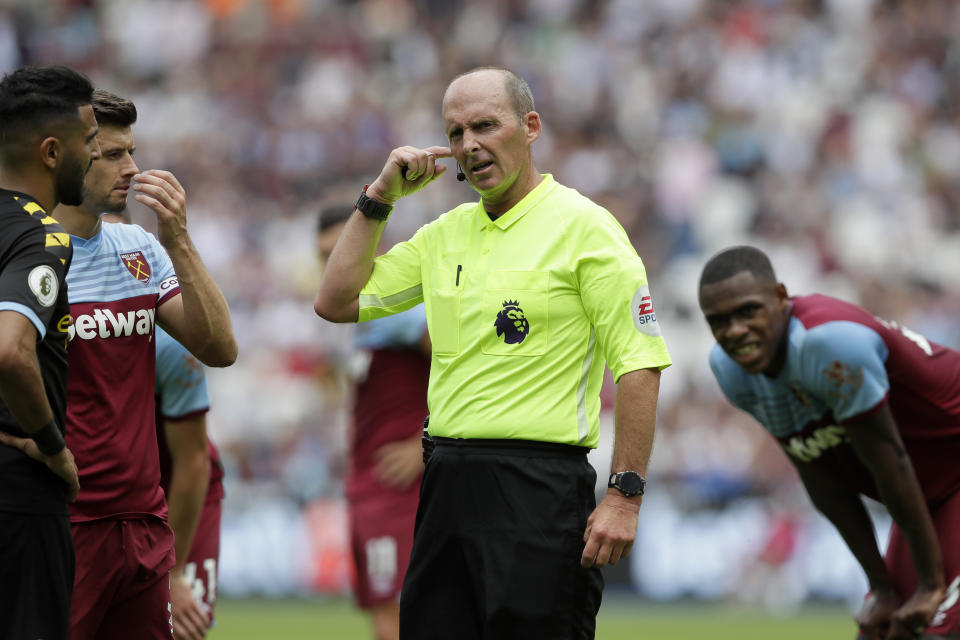 Referee Mike Dean waits for a VAR decision on a penalty during the English Premier League soccer match between West Ham United and Manchester City at London stadium in London, Saturday, Aug. 10, 2019. (AP Photo/Kirsty Wigglesworth)