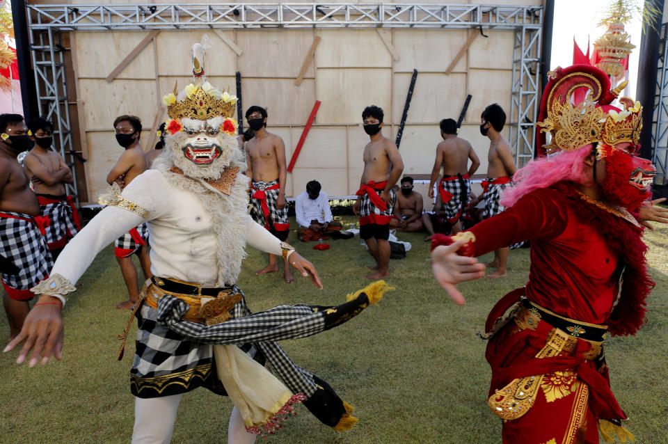 Bailarines disfrazados se preparan para ejecutar una danza tradicional durante un desfile en Bali, Indonesia, el jueves 30 de julio de 2020. (AP Foto/Firdia Lisnawati)