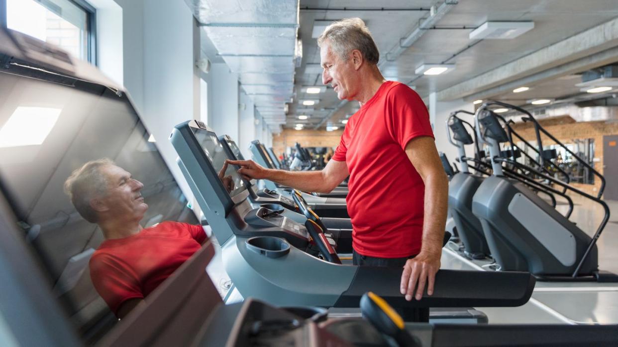 senior man adjusting speed on treadmill at rehab