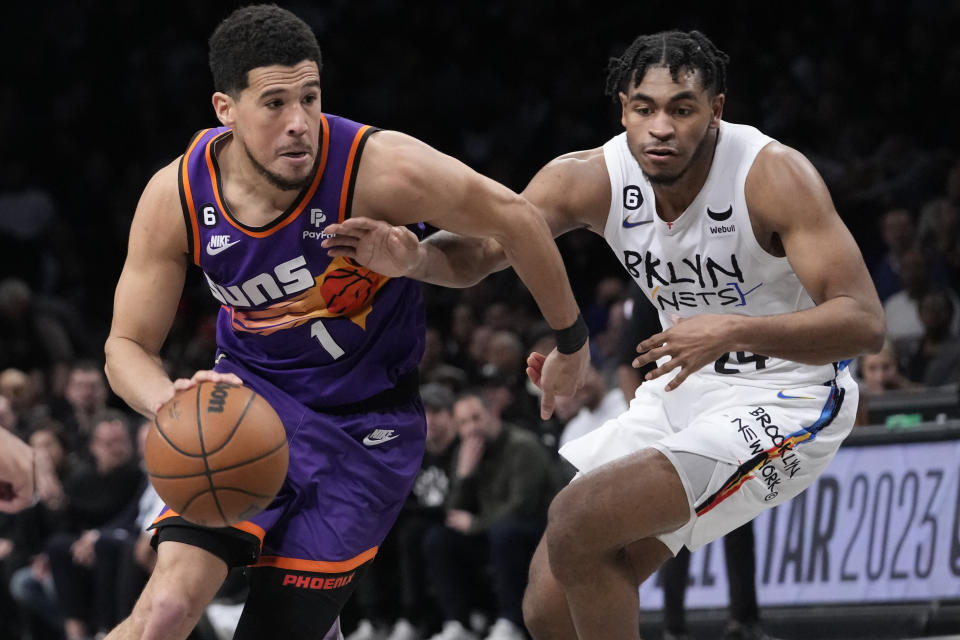 Devin Booker, base de los Suns de Phoenix, avanza junto a Cam Thomas, de los Nets de Brooklyn, en el partido del martes 7 de febrero de 2023 (AP Foto/Mary Altaffer)