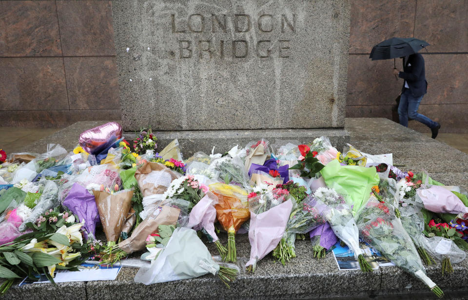 A man walks past flowers and tributes