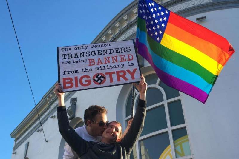 美國總統川普7月宣布禁止跨性別人士從軍後，引發外界抗議，圖為一對同志情侶手拿彩虹旗與標牌抗議川普的決定，標牌寫著：「禁止跨性別者從軍的唯一原因是偏執。」