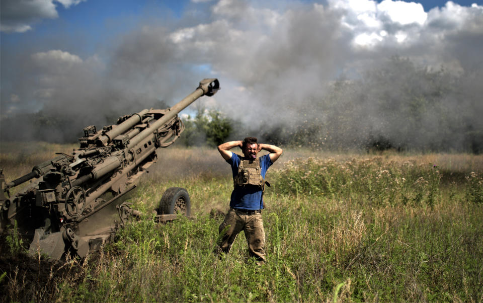 A Ukrainian soldier covers his ears after the firing of an air cannon