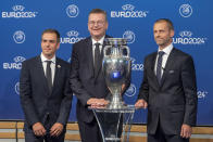 European Championship Ambassador Philipp Lahm, left, German Football Association (DFB) president Reinhard Grindel, center, and UEFA president Aleksander Ceferin, right, pose with the UEFA Euro trophy after it was announced that Germany was elected to host the Euro 2024 fooball tournament during a ceremony, at the UEFA Executive Committee at the UEFA Headquarters, in Nyon, Switzerland, Thursday, Sept.27, 2018. (Martial Trezzini/Keystone via AP)