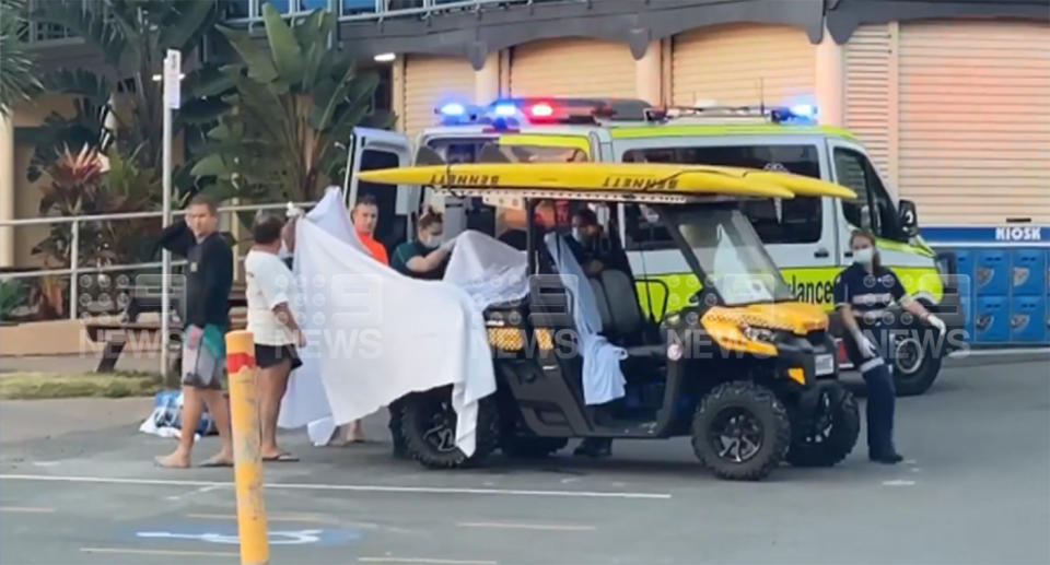 The victim of a shark attack at Greenmount Beach is loaded into an ambulance by paramedics.