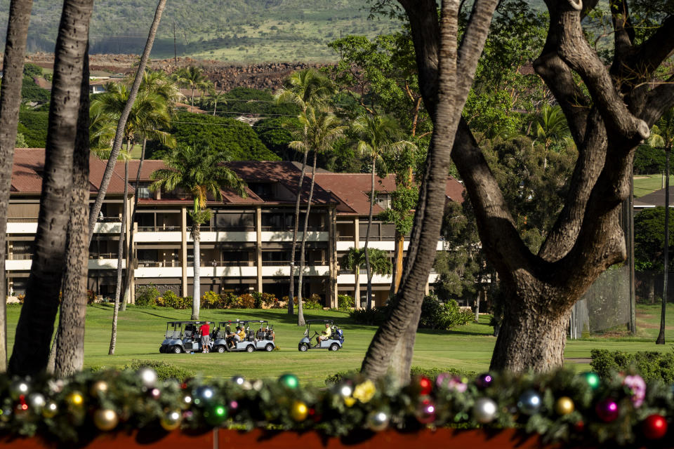 People drive golf carts through the Ka'anapali Golf Courses, Wednesday, Dec. 6, 2023, in Lahaina, Hawaii. Residents and survivors still dealing with the aftermath of the August wildfires in Lahaina have mixed feelings as tourists begin to return to the west side of Maui. (AP Photo/Lindsey Wasson)
