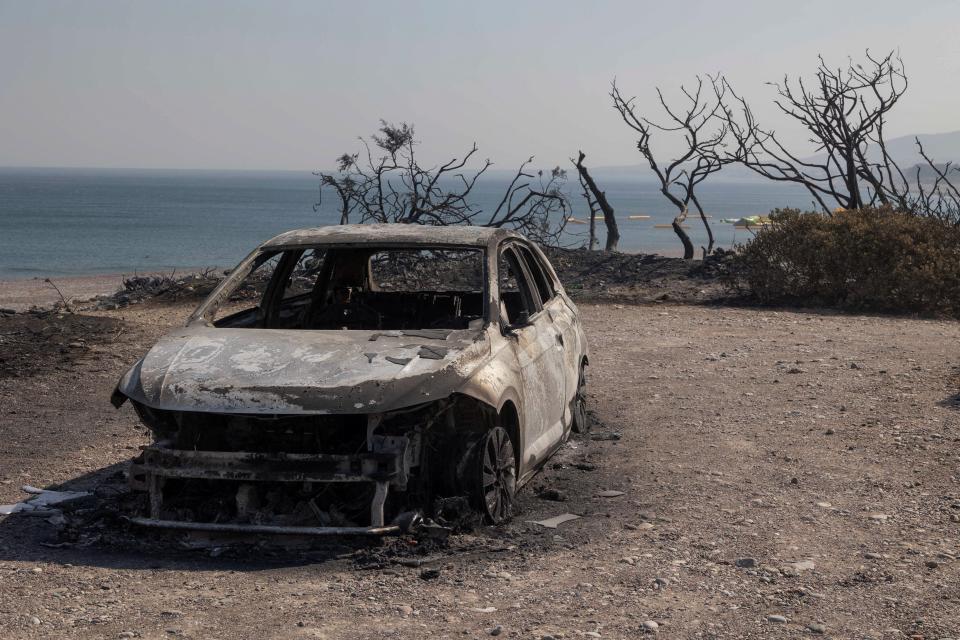 A burned car is seen on a beach in the village of Kiotari, as a wildfire burns on the island of Rhode (REUTERS)