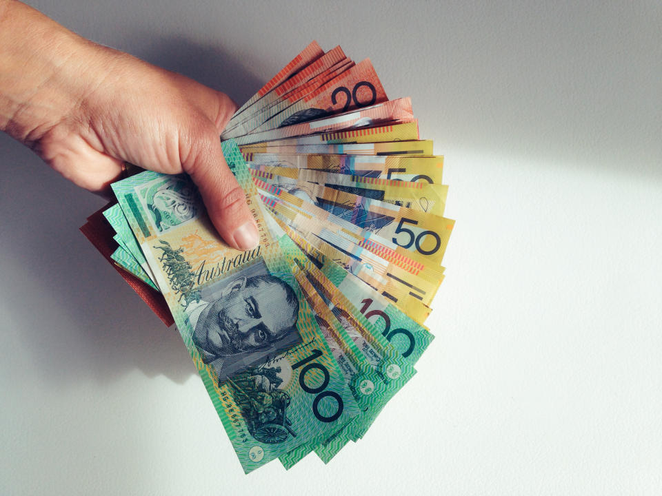 Person holding onto a large sum of money in the form of various banknotes