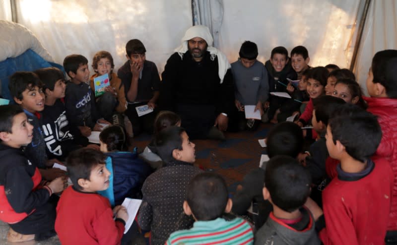 Students sit together at a makeshift school in a tent in Azaz