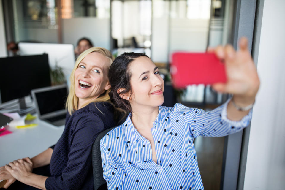 Two friends having fun at work. (Getty Images)