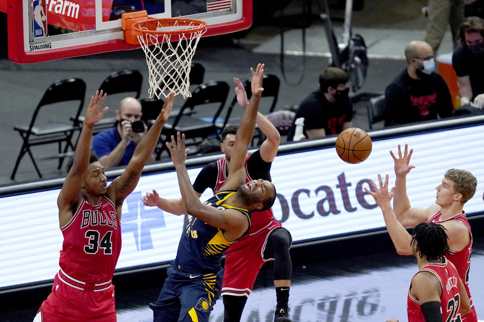Indiana Pacers' T.J. Warren, center, falls backward after being fouled by Chicago Bulls' Wendell Carter Jr. (34) during the first half of an NBA basketball game Saturday, Dec. 26, 2020, in Chicago. (AP Photo/Charles Rex Arbogast)