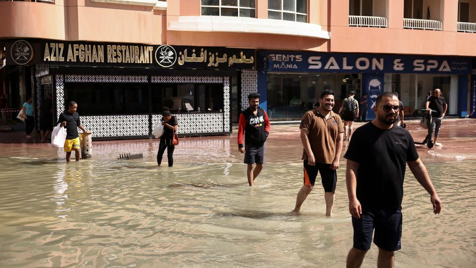 People walk through floodwater caused by heavy rains in Dubai on April 17, 2024.  -Amr Alfiky/Reuters