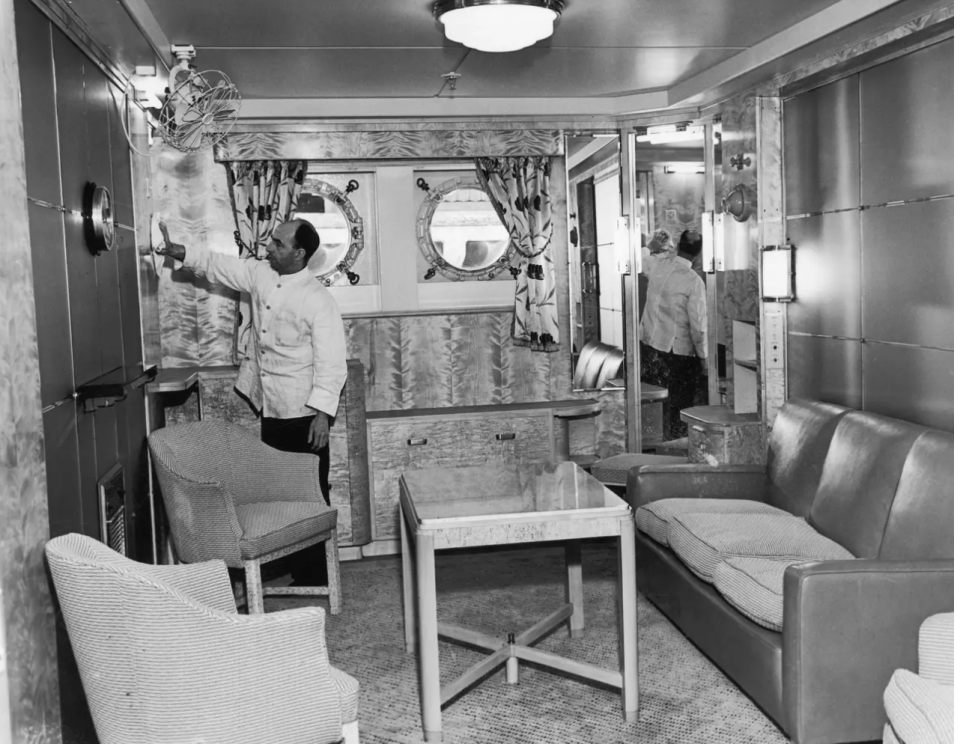 Ein Angestellter verleiht der Privatlounge in einer Kabine auf der Mauretania den letzten Schliff. - Copyright: Fox Photos/Hulton Archive/Getty Images