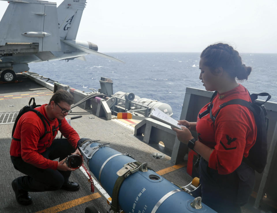 In this Wednesday, May 15, 2019, photo released by the U.S. Navy, Aviation Ordnanceman 3rd Class Alexandrina Ross, right, and Aviation Ordnanceman Airman Hunter Musil, left, inspect a bomb on the USS Abraham Lincoln while it sails in the Arabian Sea. U.S. diplomats warned Saturday, May 18, 2019, that commercial airliners flying over the wider Persian Gulf faced a risk of being "misidentified" amid heightened tensions between the U.S. and Iran. (Mass Communication Specialist Seaman Michael Singley, U.S. Navy via AP)