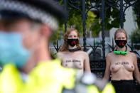 Topless activists from the Extinction Rebellion climate change group are monitored by police officers after locking themselves to the railings at a demonstration outside UK's parliament in central London on September 10, 2020 on the final day of their new series of 'mass rebellions'. - Climate change protesters have put on 10 days of demonstrations, held across the country by activist group Extinction Rebellion. (Photo by Niklas HALLE'N / AFP) (Photo by NIKLAS HALLE'N/AFP via Getty Images)