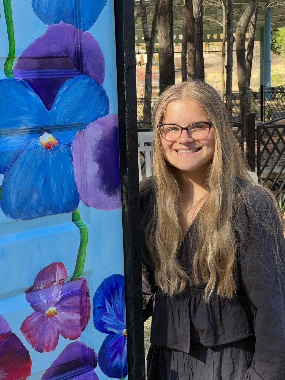 Highland School of Techology ninth-grader Sasha Kellogg poses next to her door she painted, now on display at Daniel Stowe Botanical Garden.