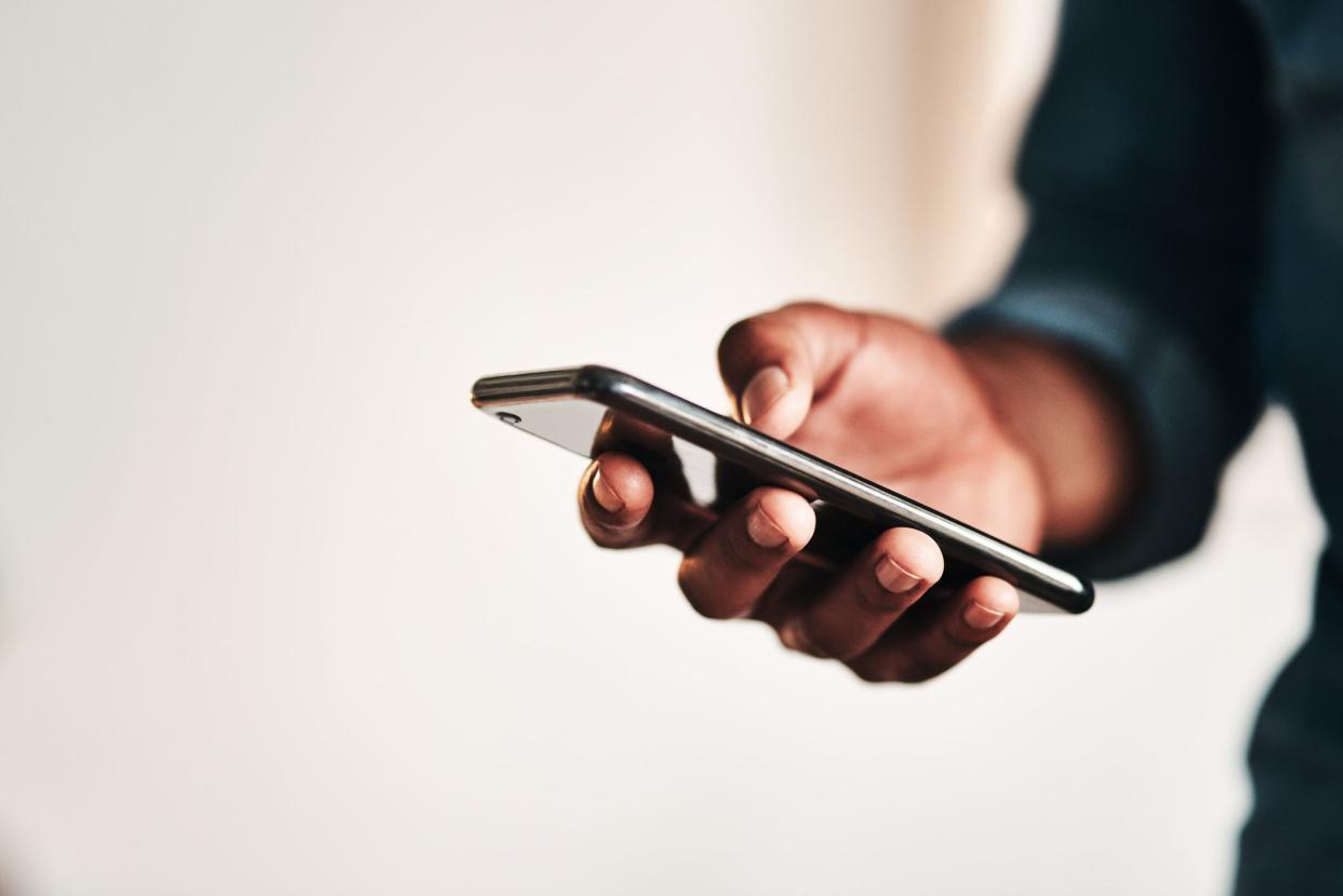 Cropped shot of an unrecognizable businessman standing alone in his home office and texting on his cellphone