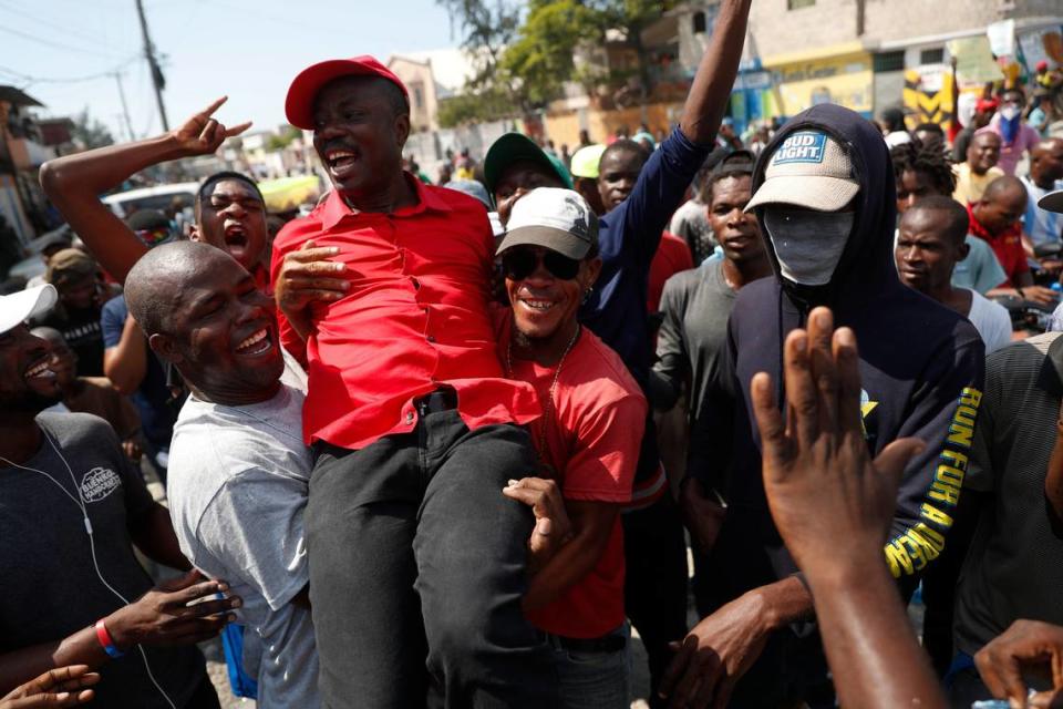 Opposition politician Jean-Charles Moïse is lifted by supporters who came to greet him from the roadside, as he leads several hundred protesters through the Tabarre neighborhood toward the United States embassy in Port-au-Prince, Haiti, Thursday, Oct. 17, 2019. Rebecca Blackwell/AP